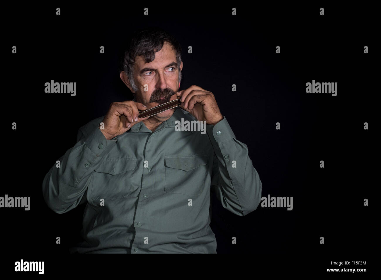 Portrait (low key) of an old Ukrainian peasant playing mouth organ Stock Photo