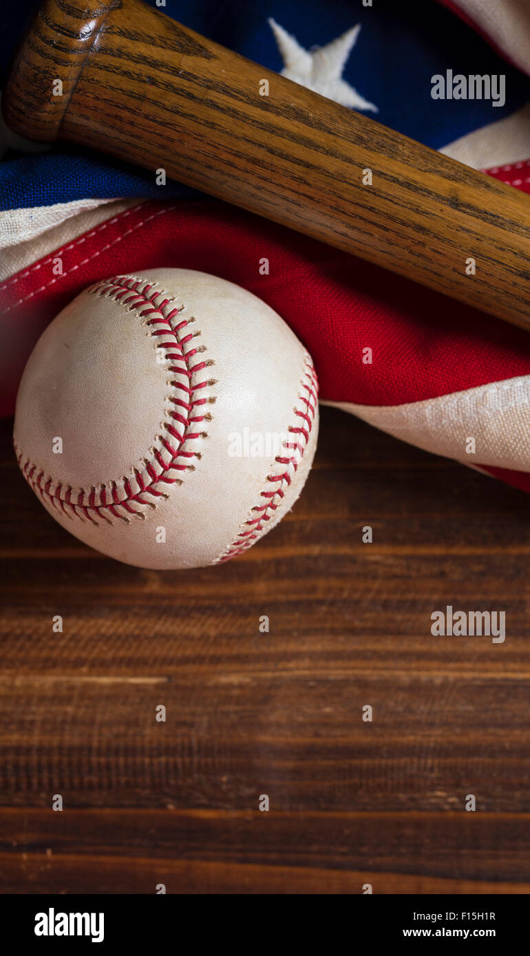 An old, antique American flag with vintage baseball equipment on a wooden bench Stock Photo