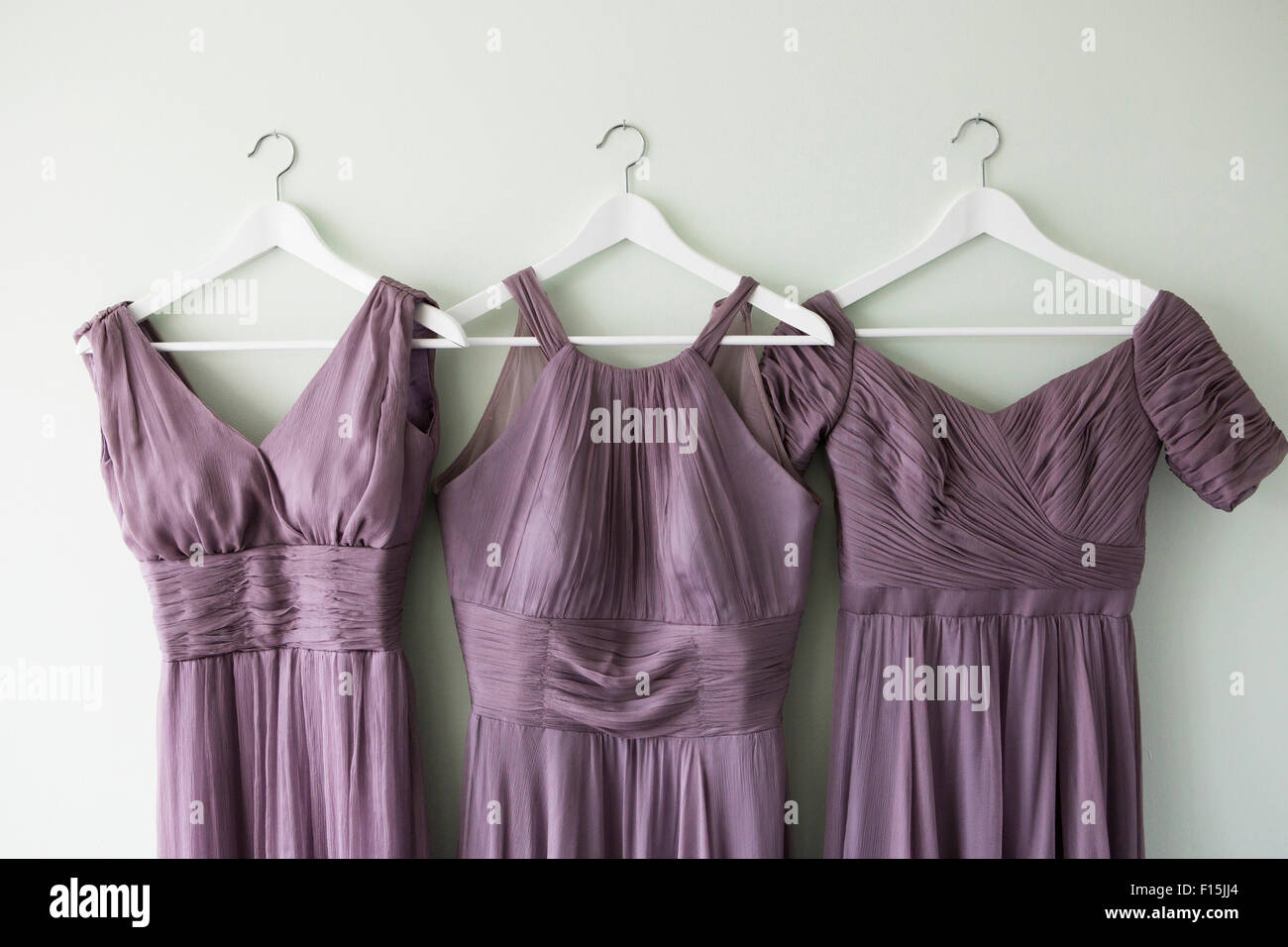 Three Bridesmaid Dresses Hanging on Wall Stock Photo - Alamy