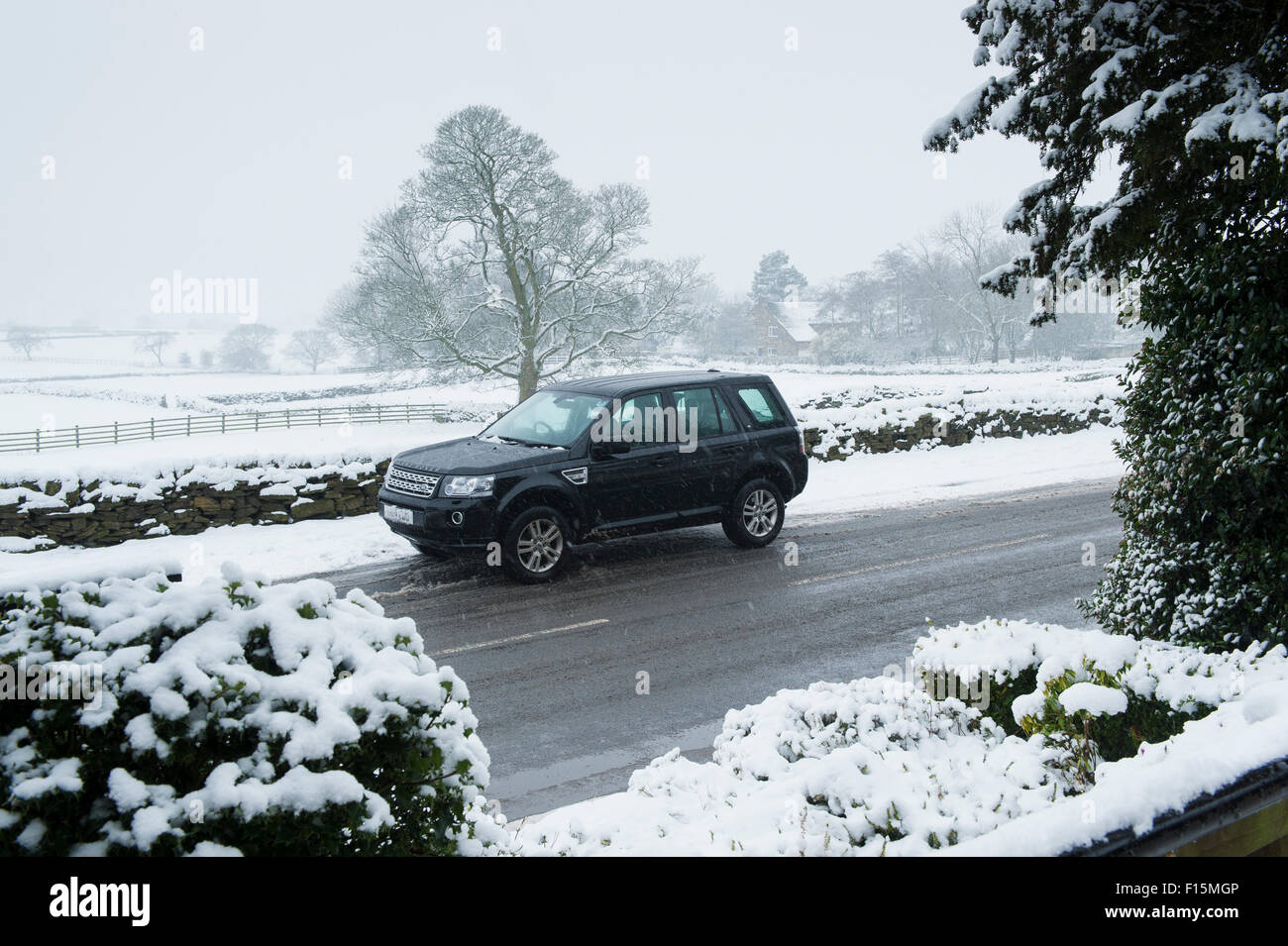 Snowing & a Land Rover Freelander 2, four-wheel drive vehicle (4x4) is parked on a snow-covered countryside road in winter - Yorkshire, England, UK. Stock Photo