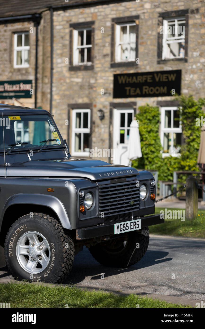 Front of clean, shiny, grey, Land Rover Defender (iconic, rugged 4x4 vehicle) parked in sunny spot on a Yorkshire Dales road - Burnsall, England, UK. Stock Photo