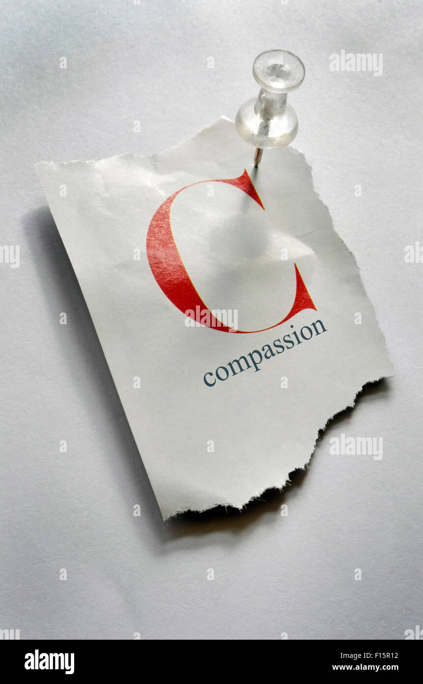 Close-up of Torn Page with C and Compassion on it, Pinned to Board Stock Photo