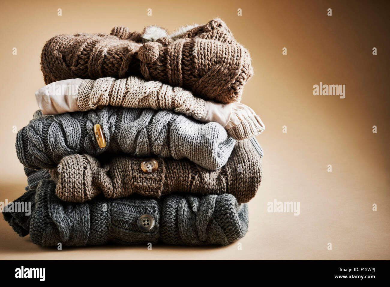 Stack of five cardigans, studio shot on brown background Stock Photo