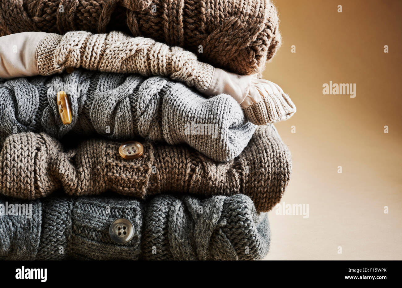 Close-up of stack of five cardigans, studio shot on brown background Stock Photo