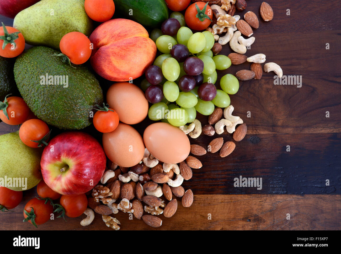 Healthy Diet with fresh fruit, apples, pears, avocados, grapes, eggs, nuts, tomatoes cucumbers on a rustic wood background. Stock Photo
