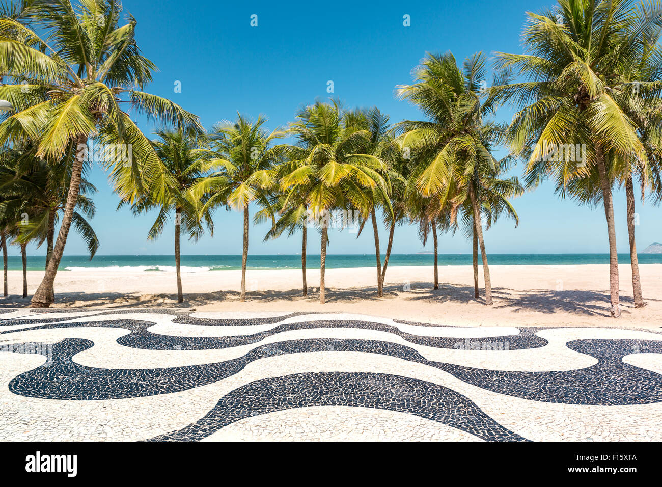 Palm trees and the iconic Copacabana beach mosaic sidewalk, in Rio de Janeiro, Brazil. Stock Photo