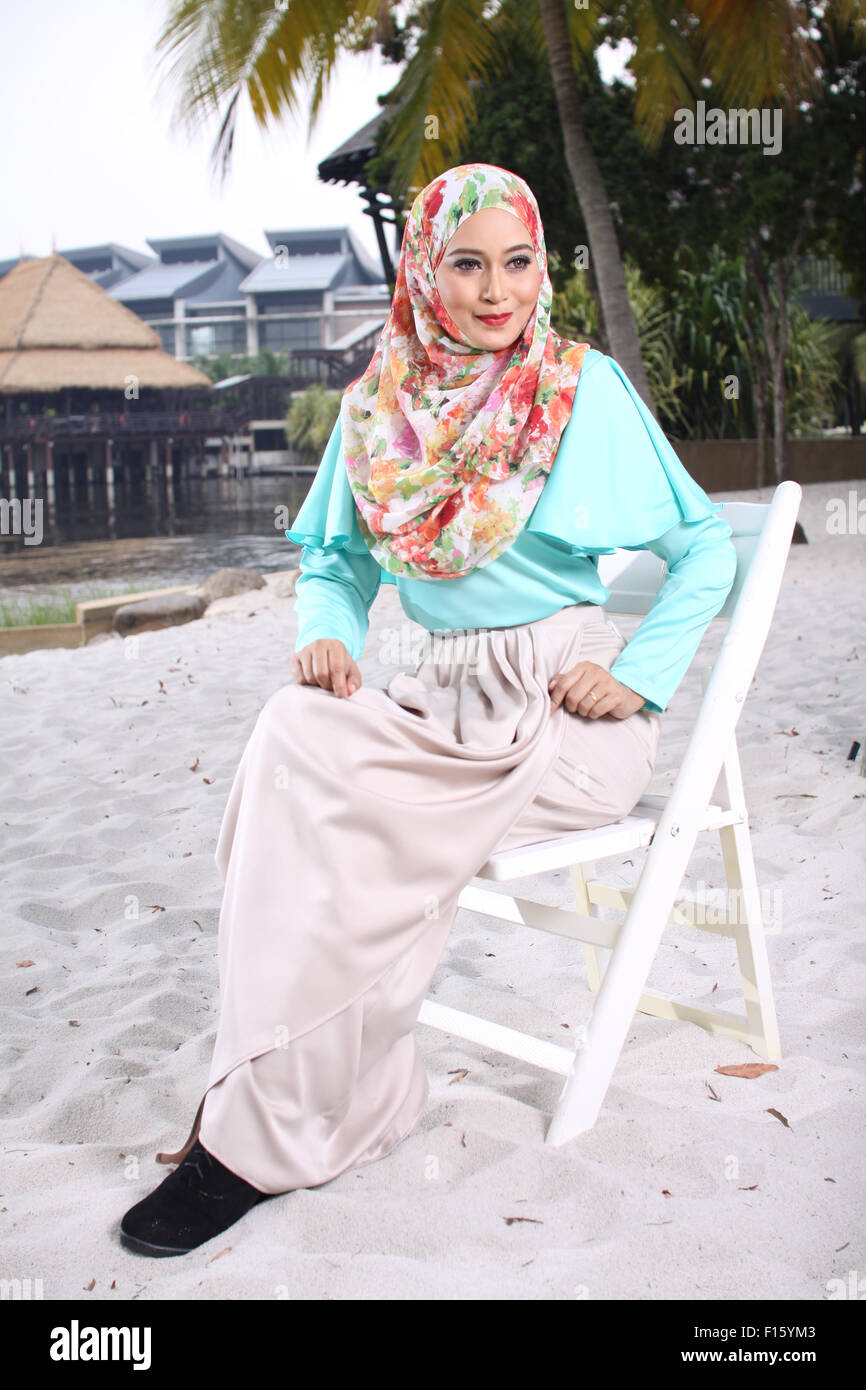 high fashion muslim women sitting at wooden white chair with beach background Stock Photo