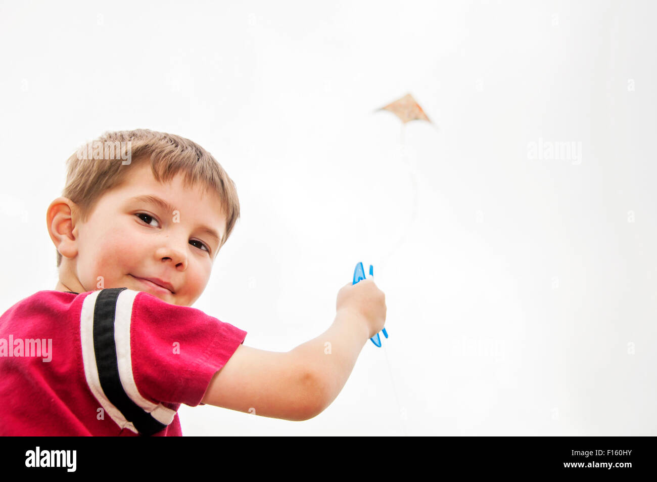 Boy flying kite looking back shoulder Stock Photo
