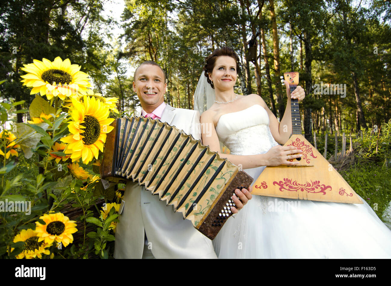 fiancee blow the balalaika,  bridegroom play on accordion, wedding  humour photo Stock Photo