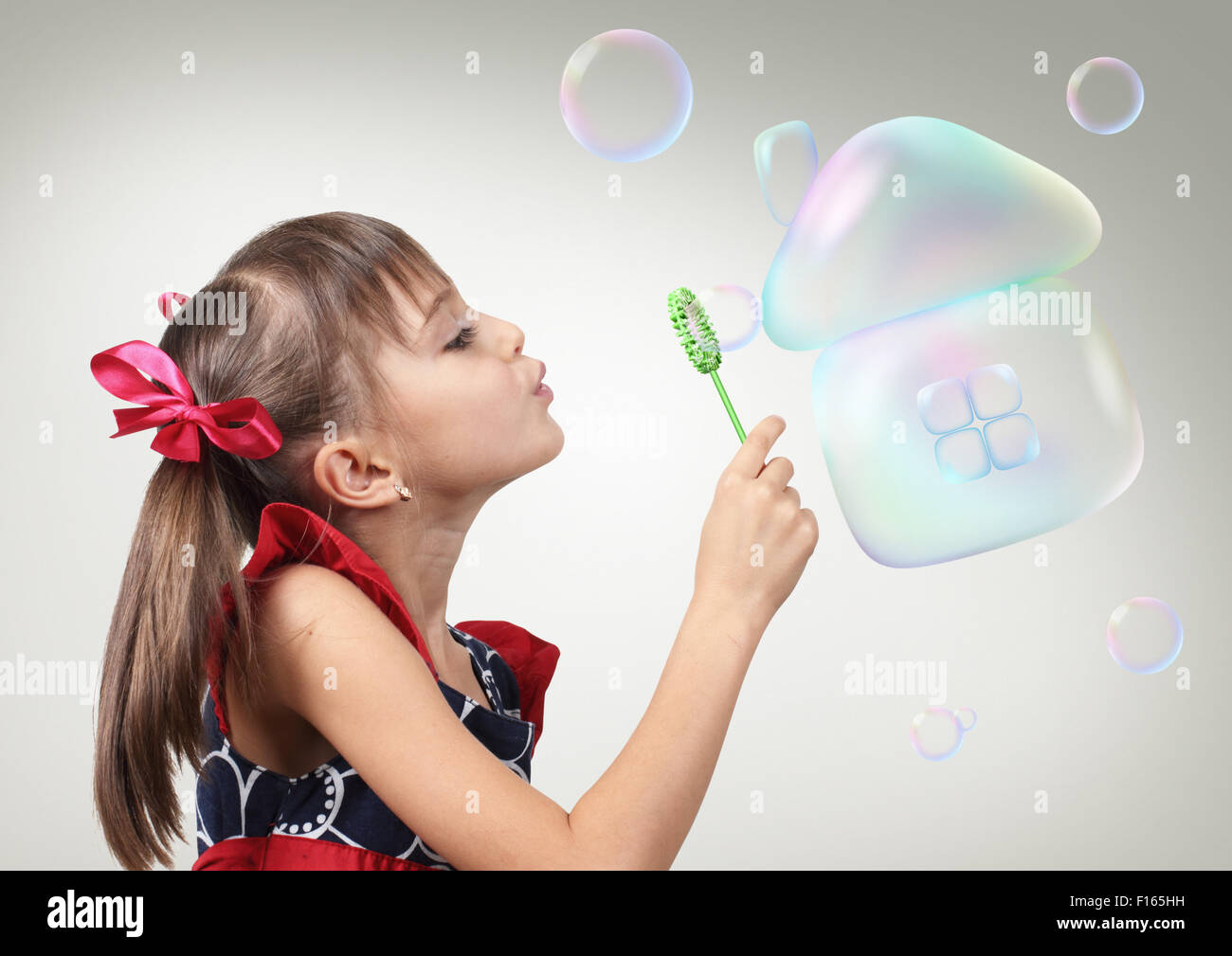 Child girl blowing soap bubble forming house, creative habitation concept Stock Photo