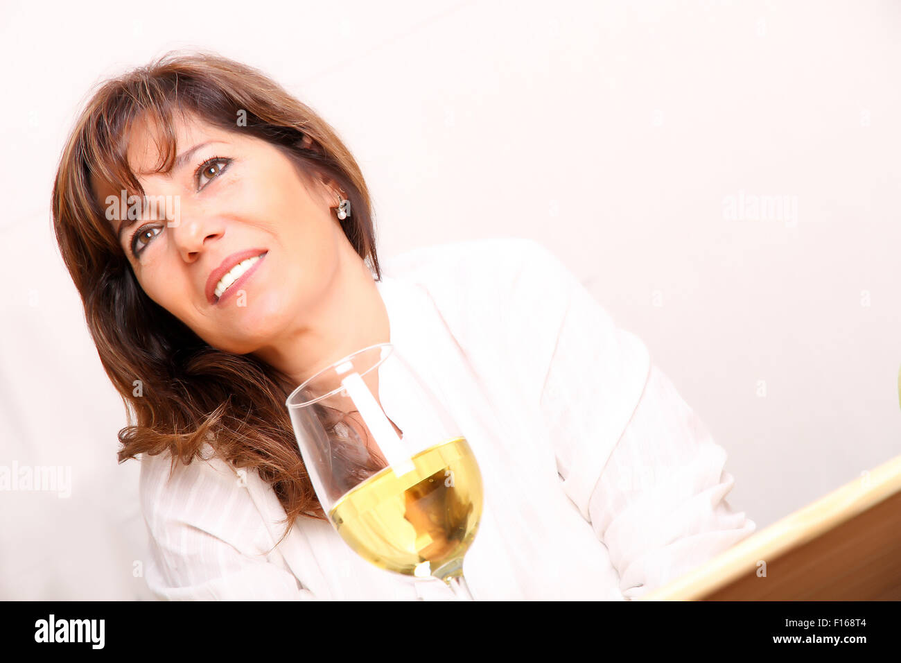 A beautiful mature woman with a glass of white wine Stock Photo - Alamy