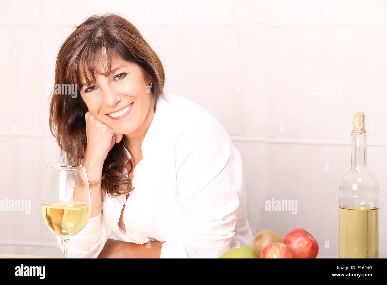 A beautiful mature woman with a glass of white wine Stock Photo - Alamy