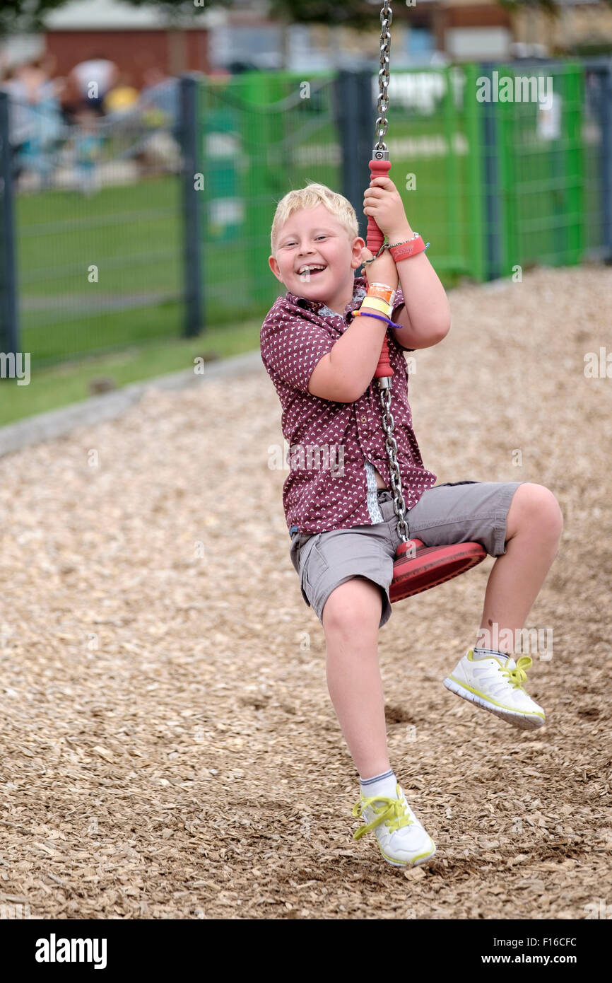 Happy six year old boy laughing on zip wire ride Stock Photo