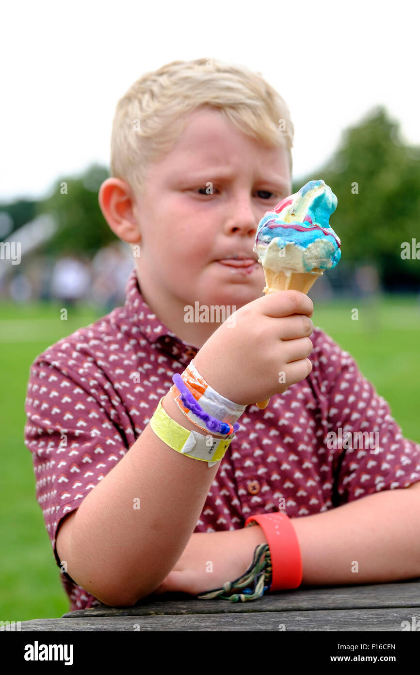 Six year old boy licking lips while eating an Ice cream cornet with added flavouring Stock Photo