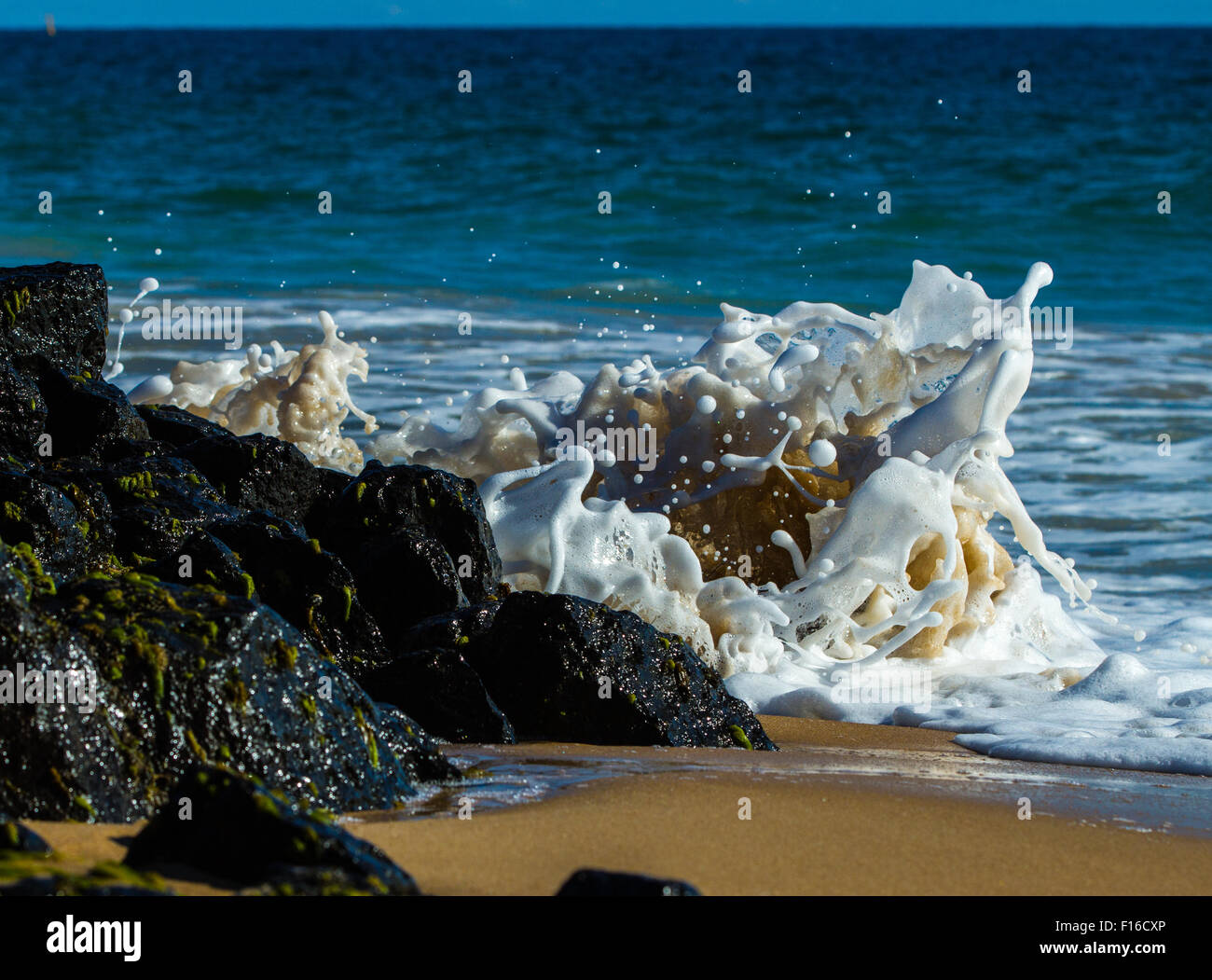 Gentle waves crashing into rocks causing a beautiful looking scene of frozen foam and water! Stock Photo