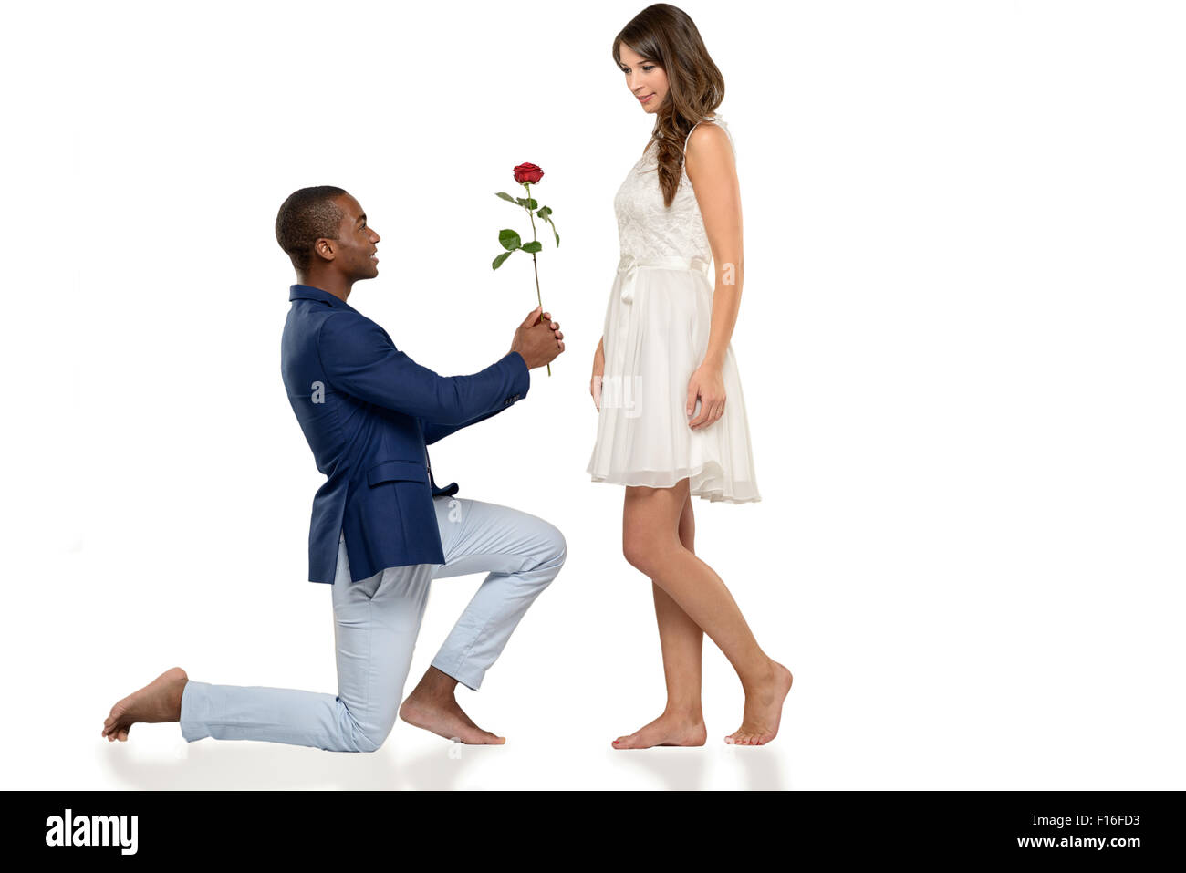 Romantic hipster barefoot young man kneeling on the floor proposing to his sweetheart declaring his undying love in a tender sce Stock Photo