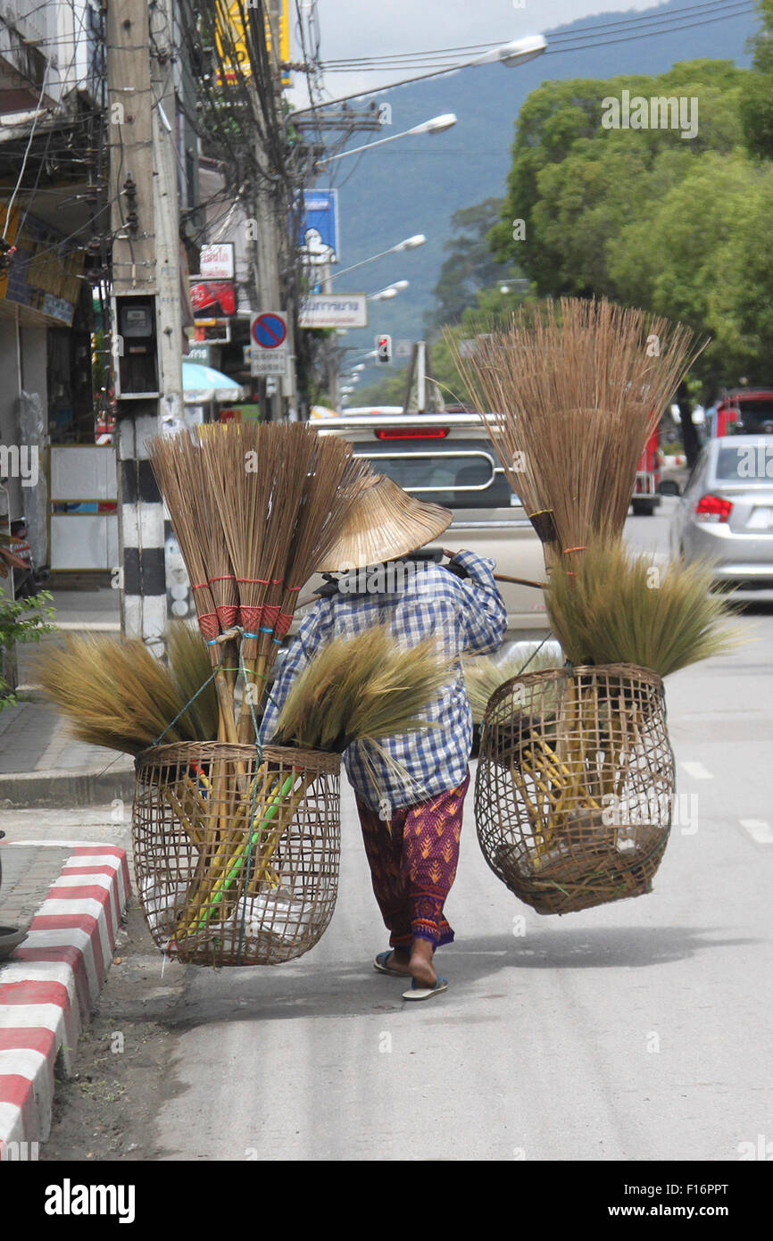 A Thai lady carries brooms in Chiang Mai, Thailand Stock Photo