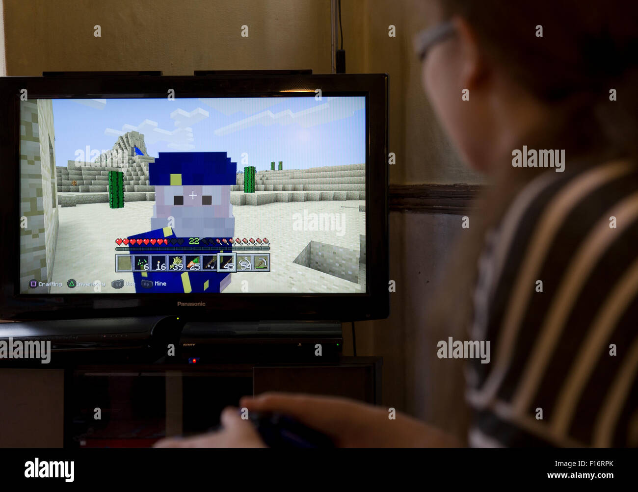 Teenage girl plays the video game Minecraft on a video consol Stock Photo