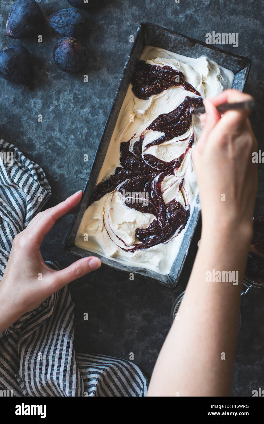 Fig swirl ice cream ready for the freezer. Womans hands adding the swirl. Stock Photo