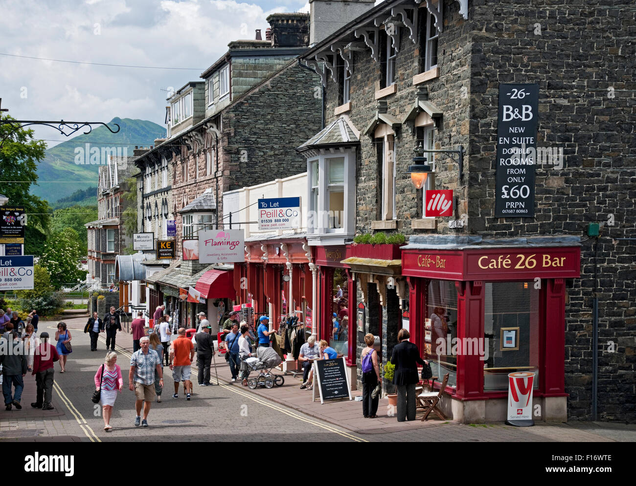 People visitors tourists walking in the street near shops stores along Lake Road in summer Keswick Cumbria England UK United Kingdom GB Great Britain Stock Photo