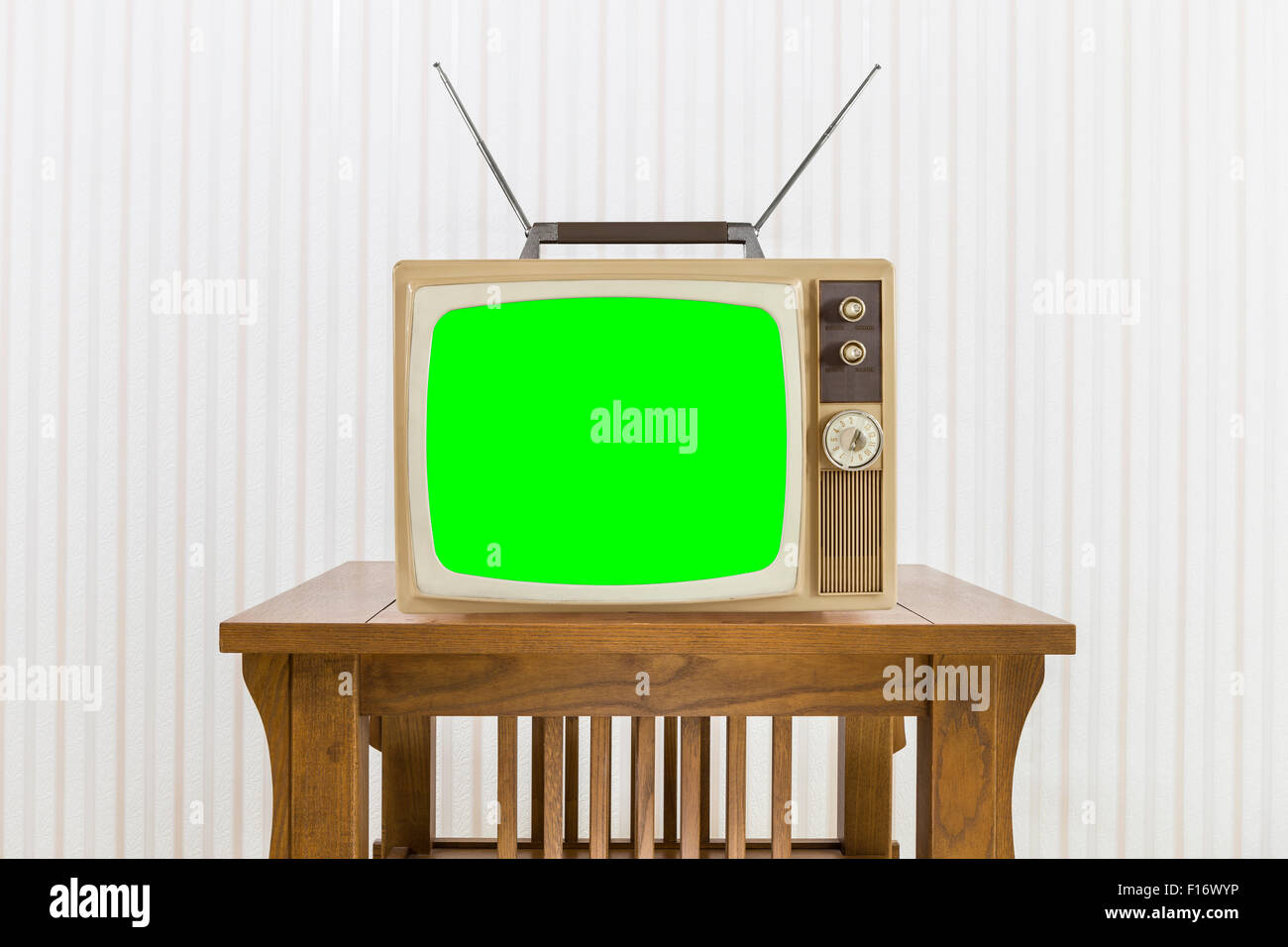 Old television with antenna on wood table with chroma screen. Stock Photo