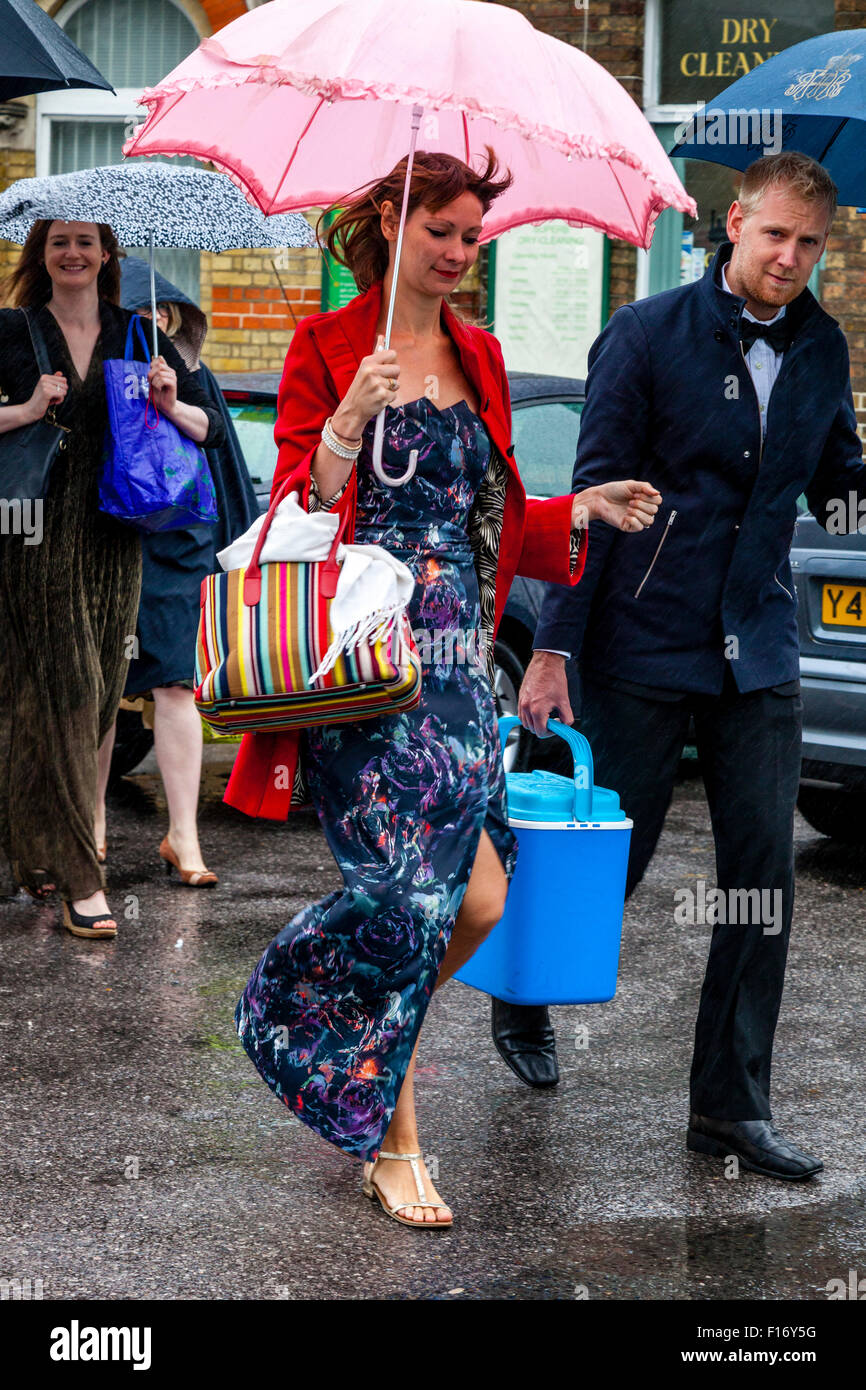 Young Opera Fans Arrive In The Pouring Rain At Lewes Station En Route To Glyndebourne Opera House, Lewes, Sussex, UK Stock Photo