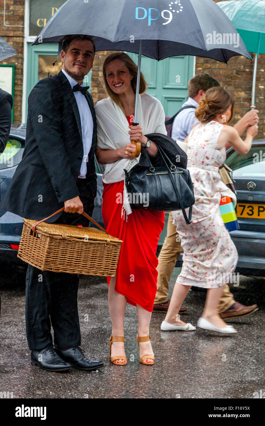 Young Opera Fans Wait In The Pouring Rain At Lewes Station For A Bus Take Them To Glyndebourne Opera House, Lewes, Sussex, UK Stock Photo