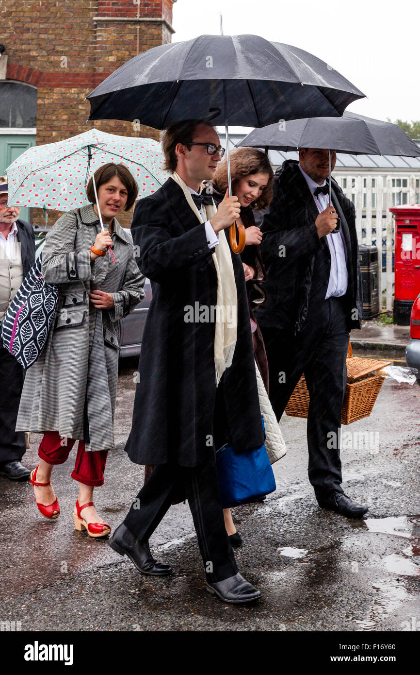 Young Opera Fans Arrive In The Pouring Rain At Lewes Station En Route To Glyndebourne Opera House, Lewes, Sussex, UK Stock Photo
