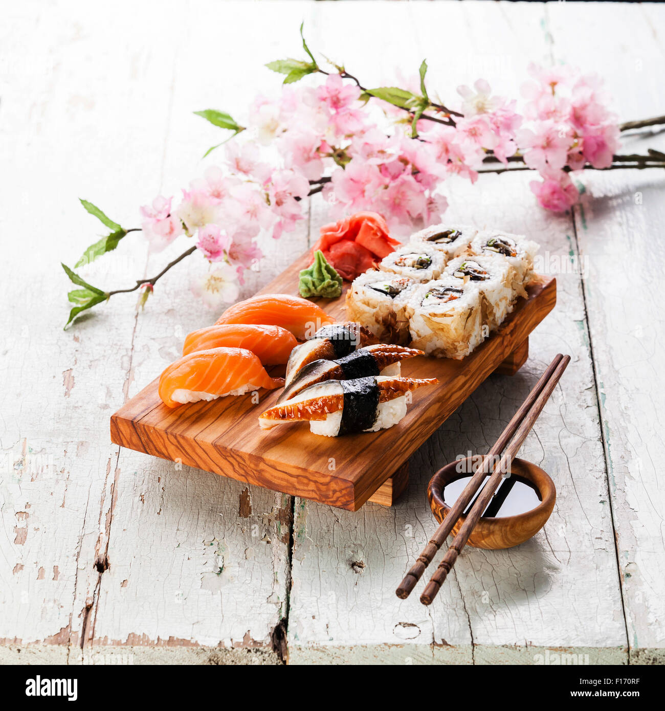Sushi Set with sashimi and sushi rolls on olive wood board on blue wooden background Stock Photo