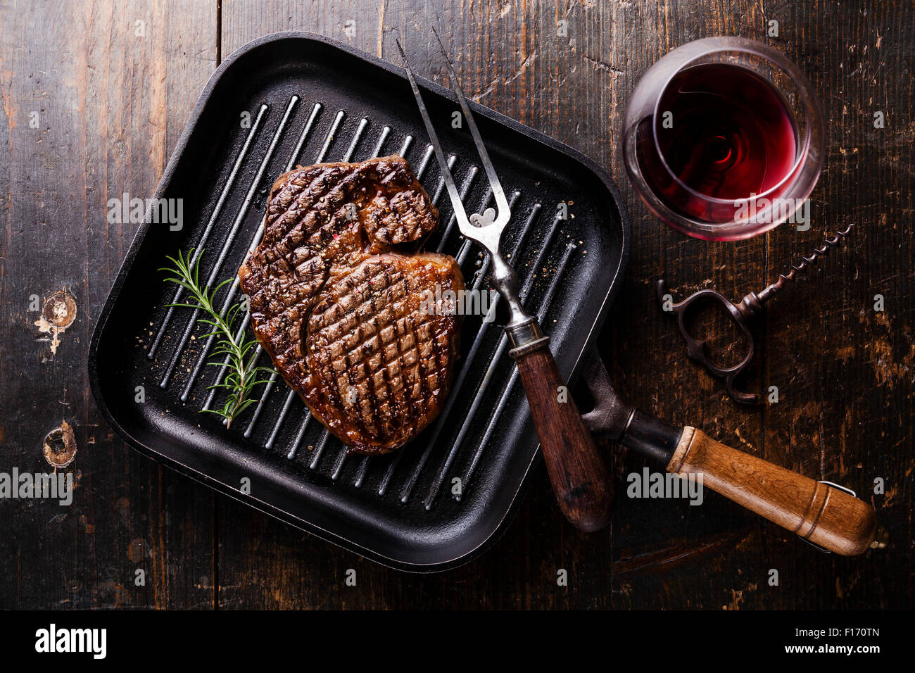 Grilled Black Angus Steak Ribeye on grill iron pan on wooden background with wine Stock Photo