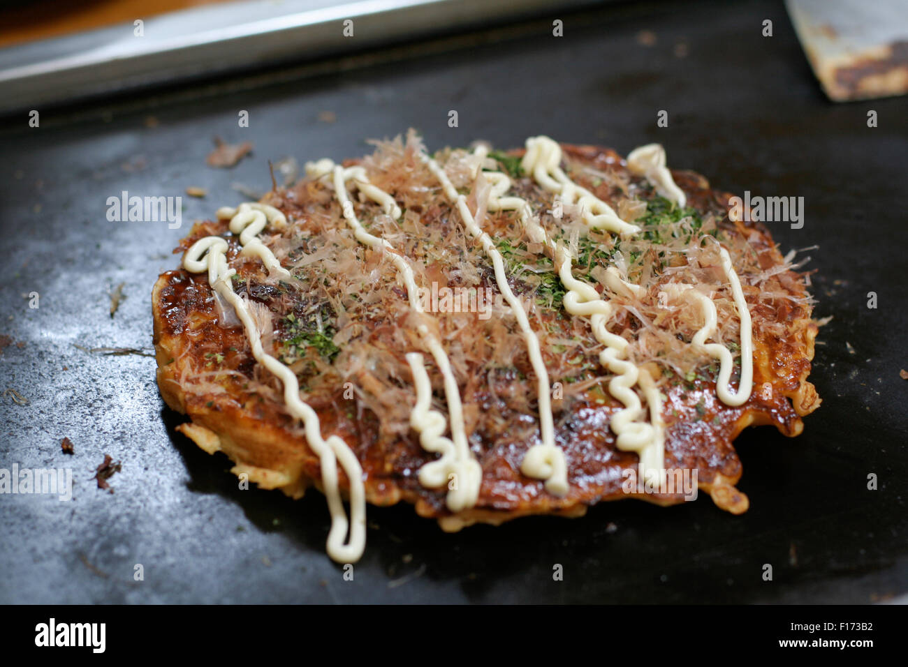 Okonomiyaki Japanese savory pancake on hotplate Stock Photo