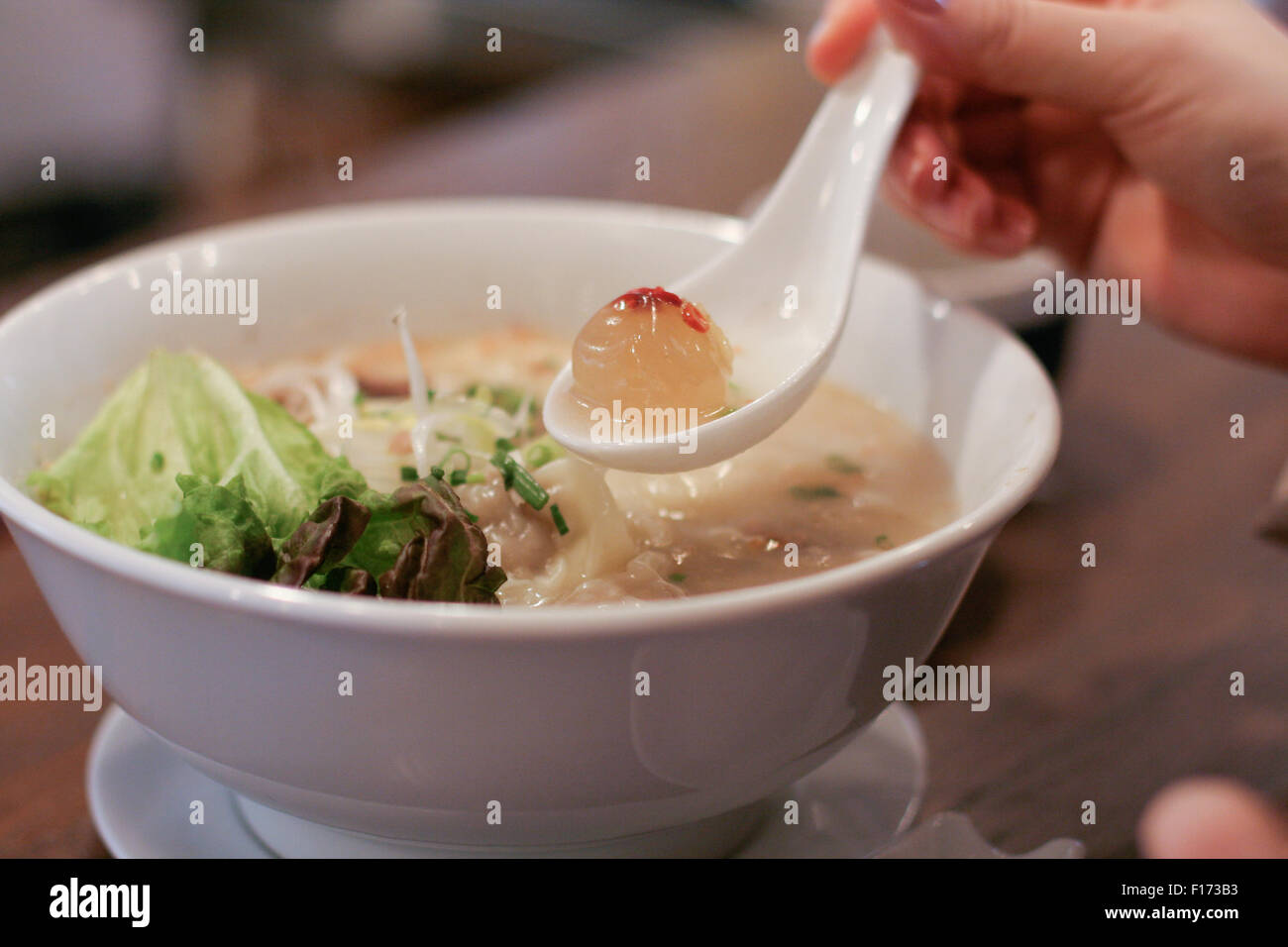 Collagen ball in spoon with Asian dumpling soup in bowl. Stock Photo