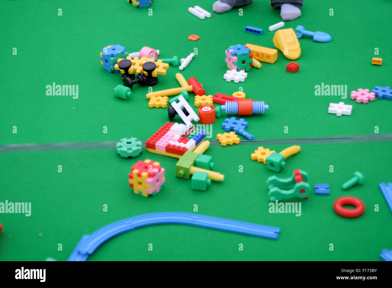 Building blocks and children toys on green floor socks feet Stock Photo