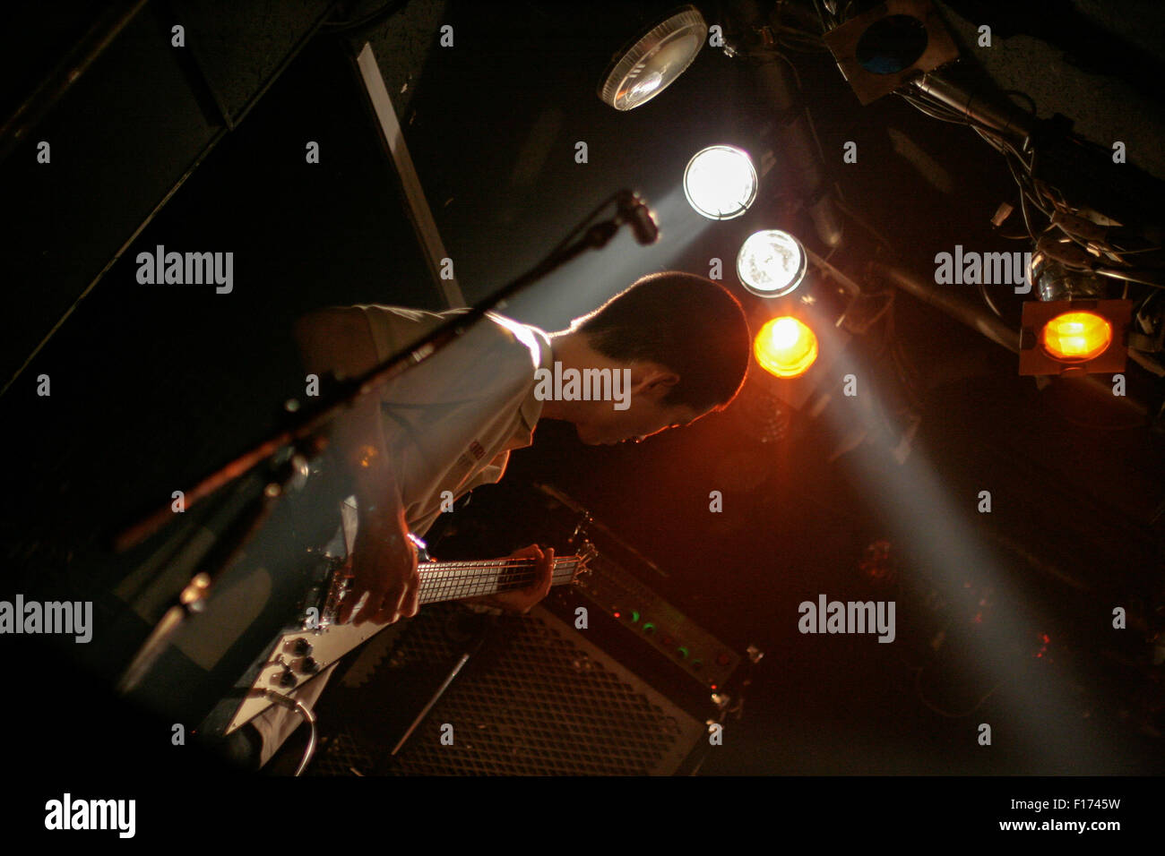 Bass guitarist playing below stage lights Stock Photo