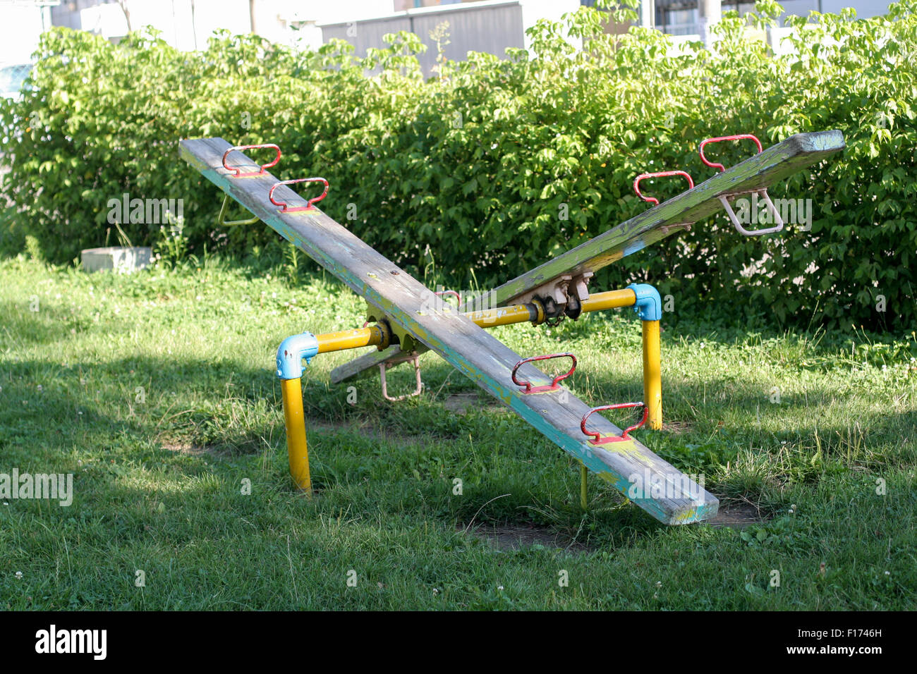 Teeter totter surrounded by grass bush background Stock Photo