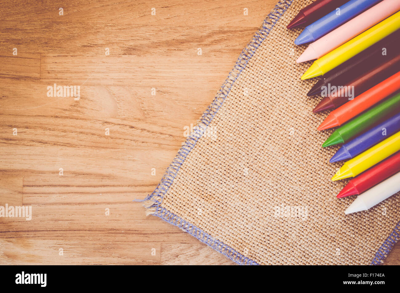 set of colored wax crayons on a natural burlap and wood background ...