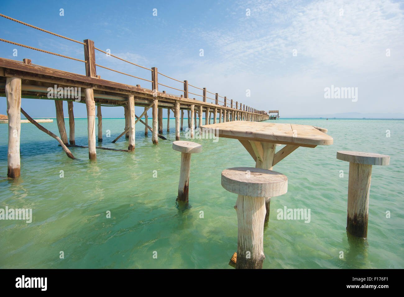 Long wooden jetty in the sea from a tropical island lagoon on beach