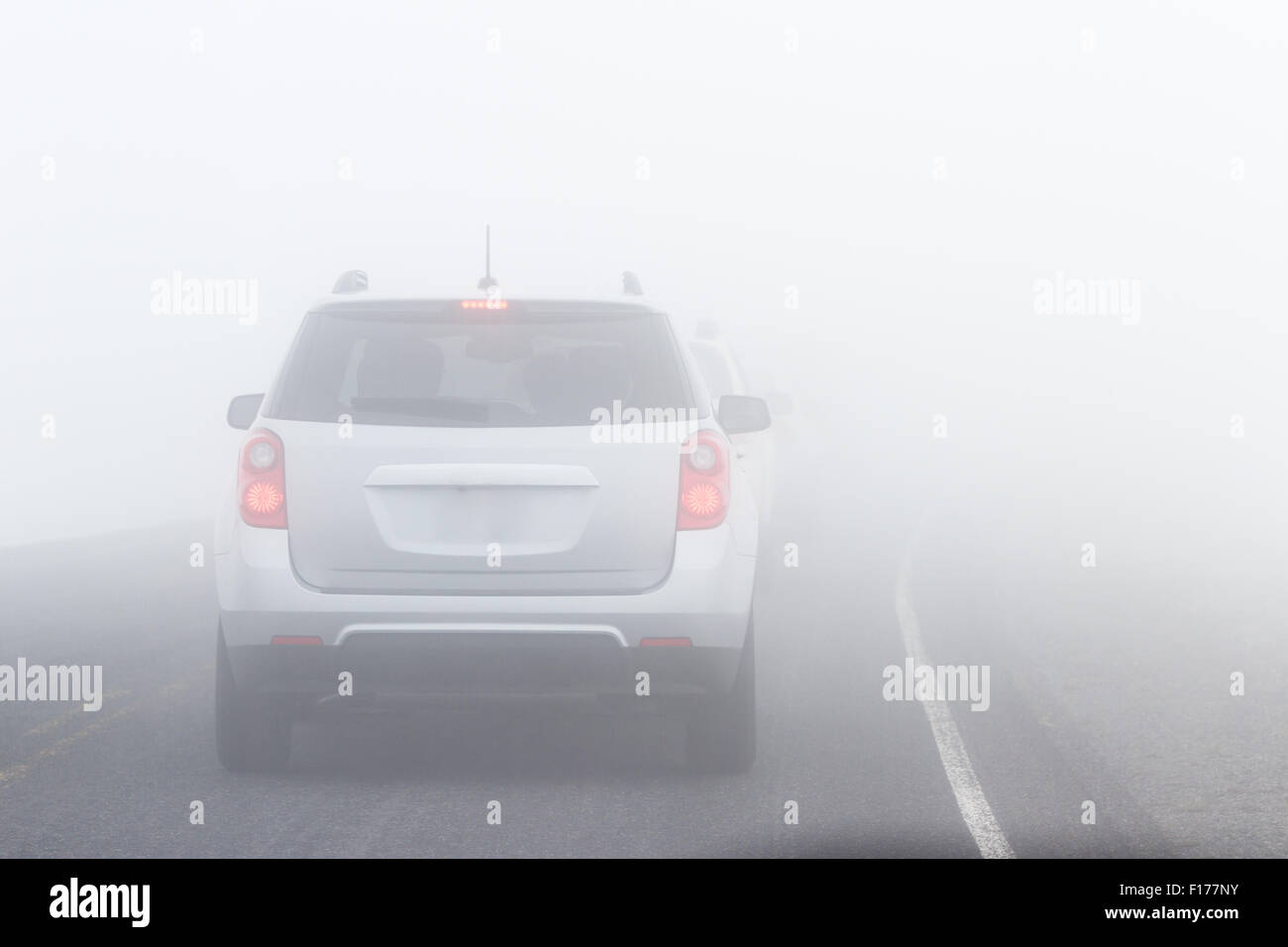 view of a car driving on a paved road with extremely limited visibility
