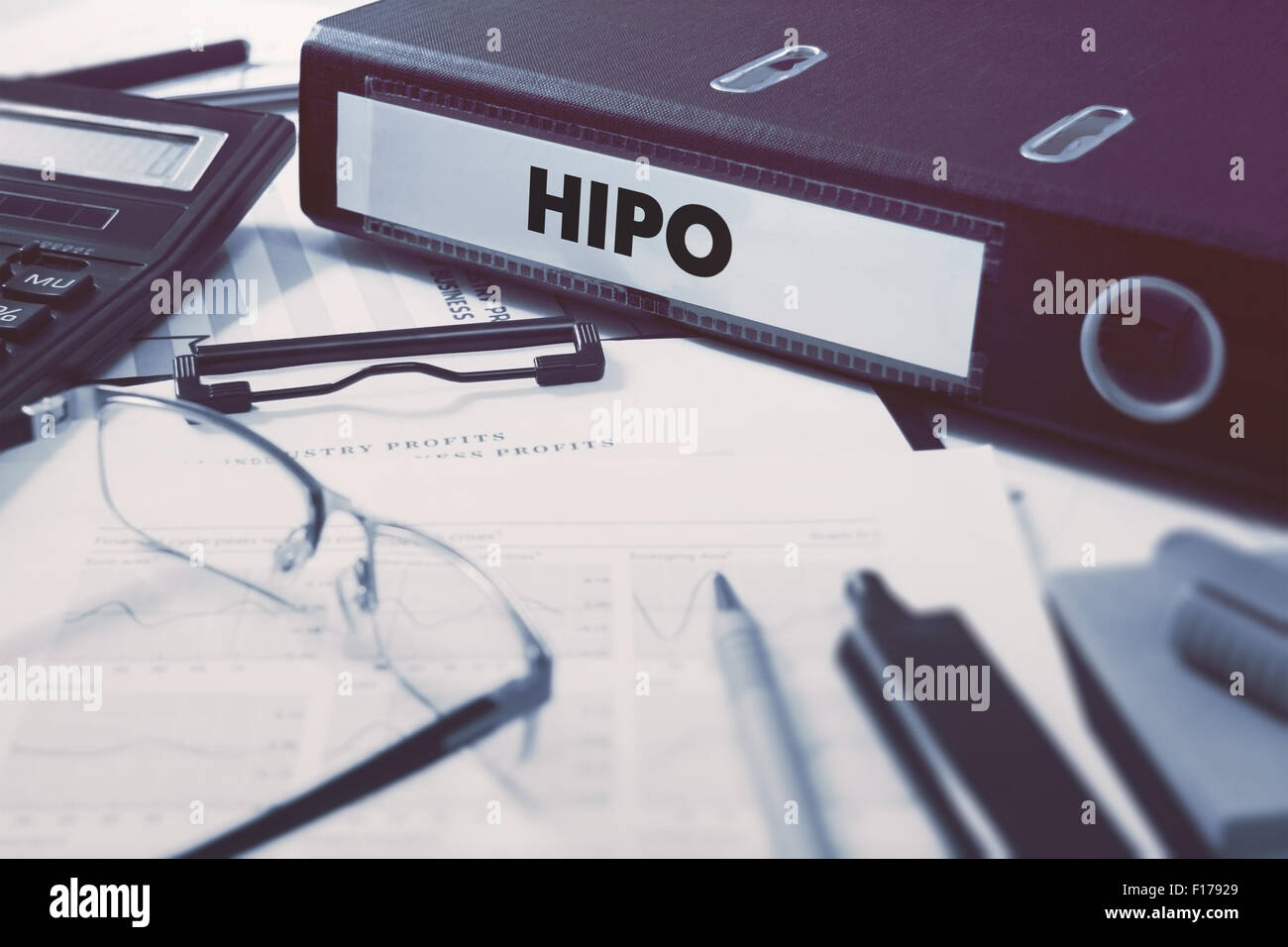 Ring Binder with inscription HiPo - High Potential - on Background of Working Table with Office Supplies, Glasses, Reports. Tone Stock Photo