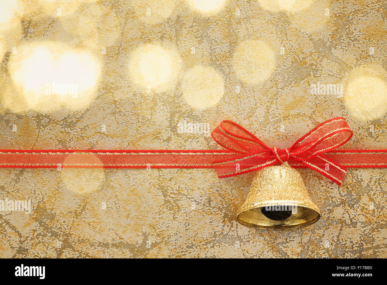 Golden jingle bell with ribbon bow on festive background Stock Photo