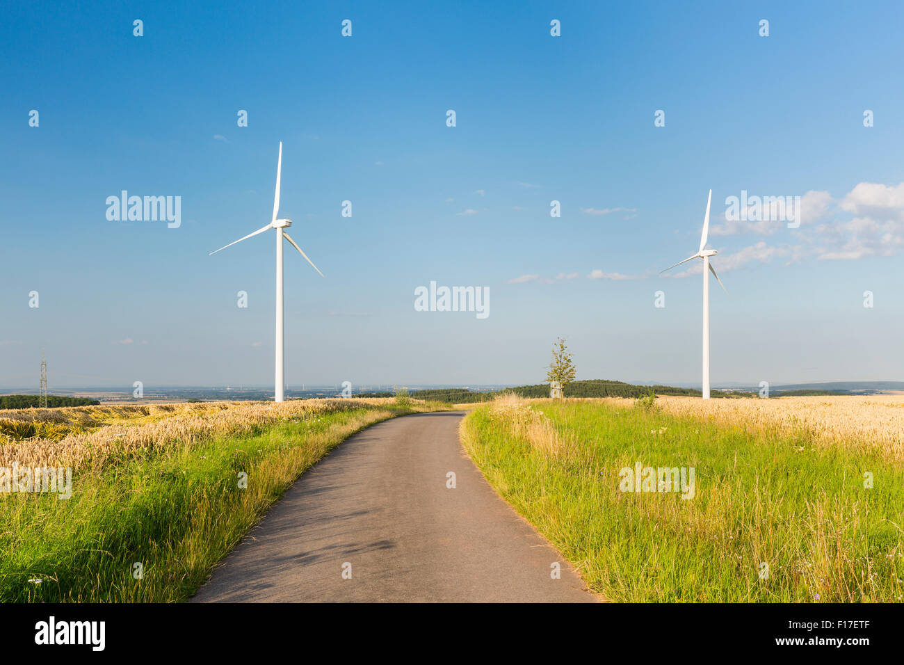 A country road leading towards some wind turbines in the Eifel, Germany. Stock Photo
