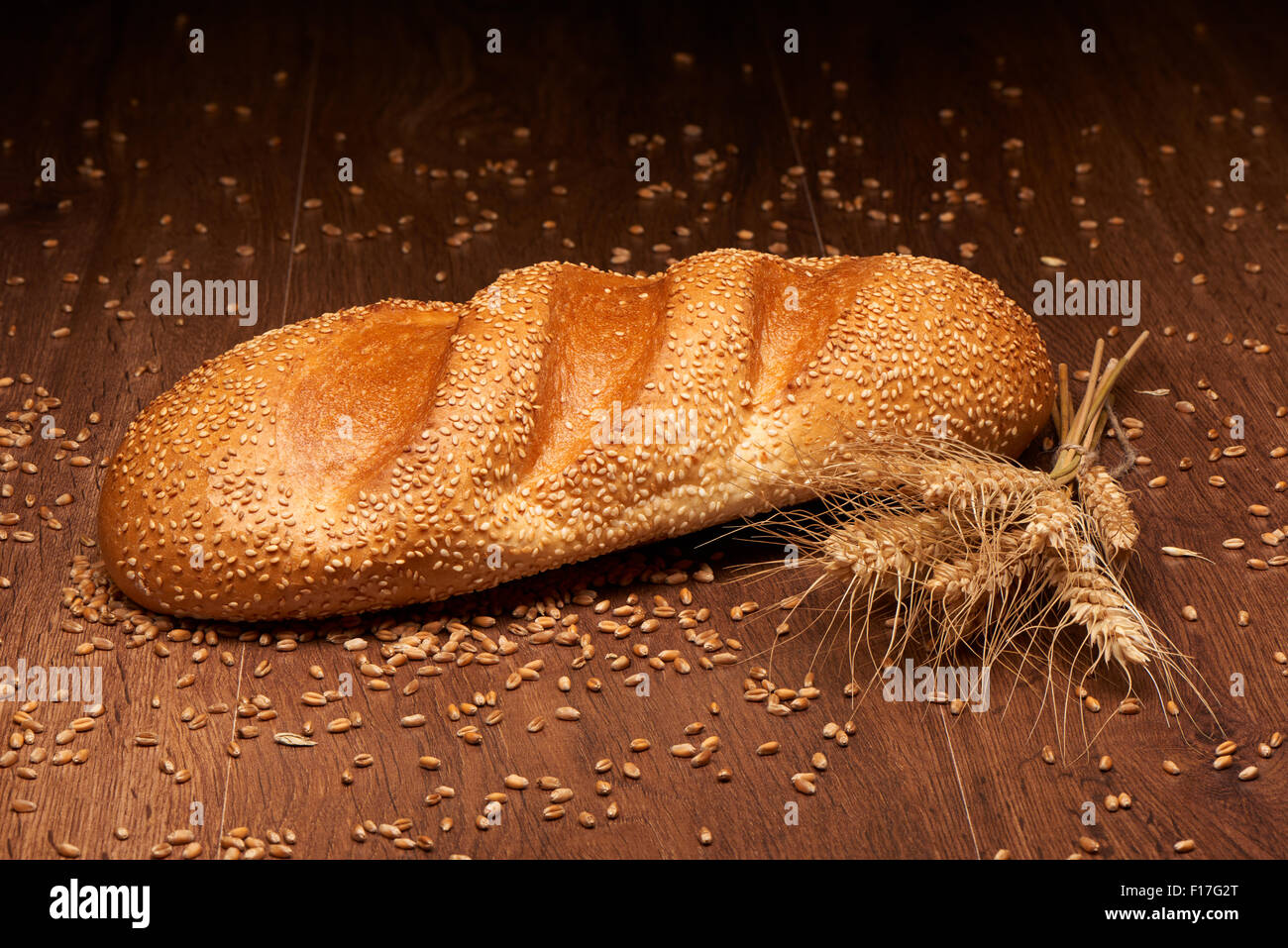 Fresh bread and wheat on dark wooden table background Stock Photo