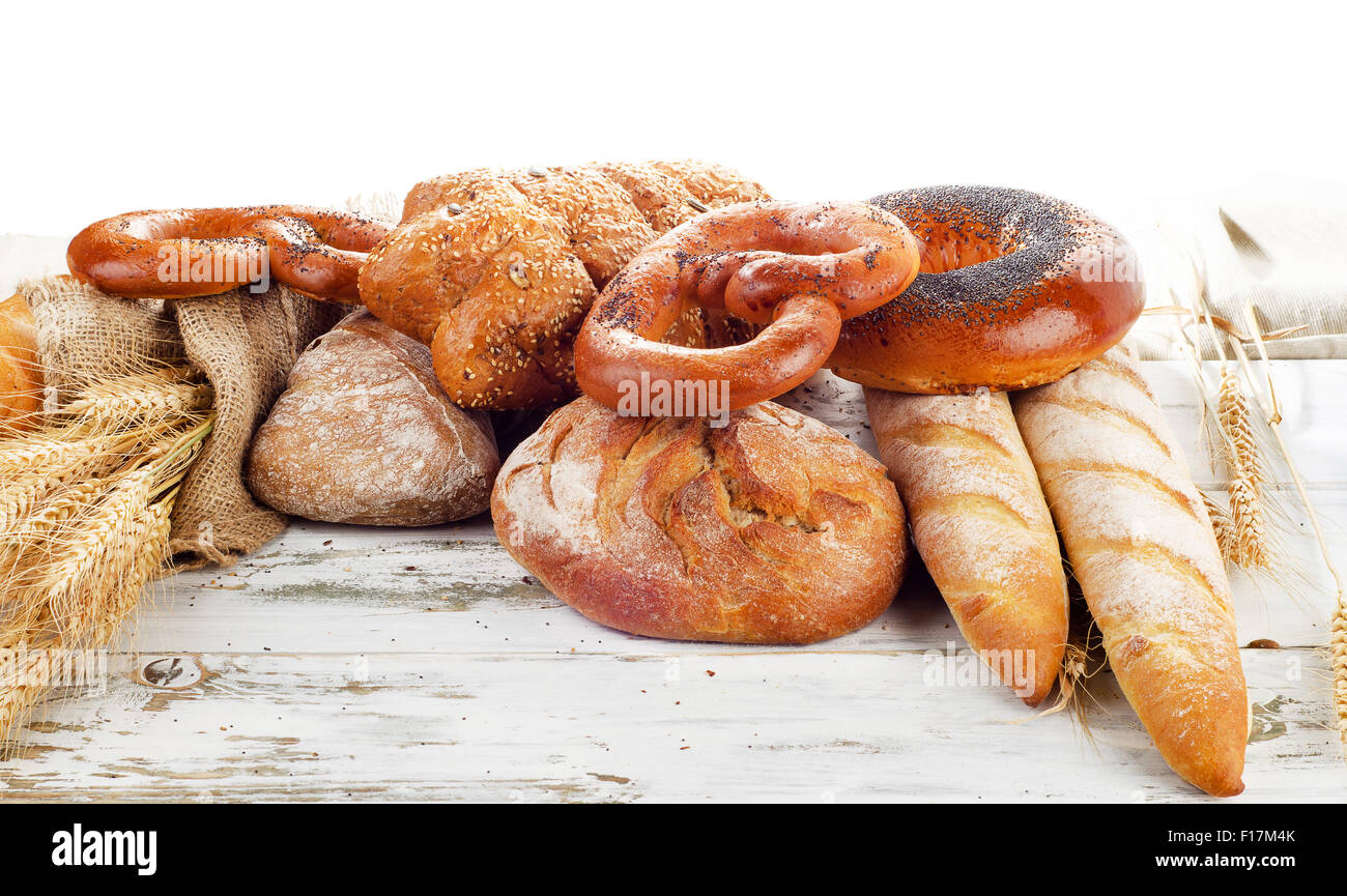 Assortment of fresh baked bread on a wooden table isolated on white ...