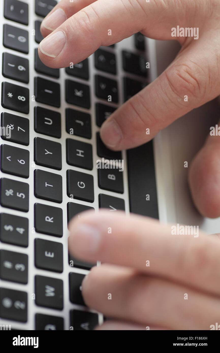 Closeup view of a  man typing on a laptop keyboard Stock Photo