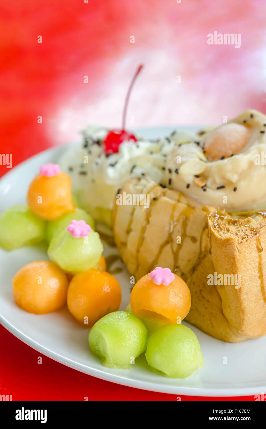 Honey toast topped  with ice cream cantaloupe and melon on dish Stock Photo
