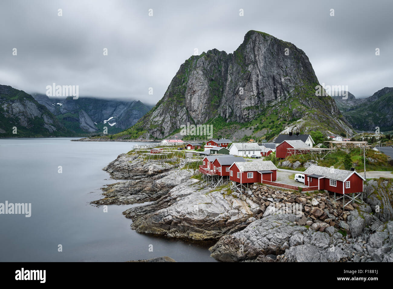 Traditional red rorbu cottages under the  Lilandstinden mountain peak in Hamnoy village, Lofoten islands, Norway. Long exposure. Stock Photo