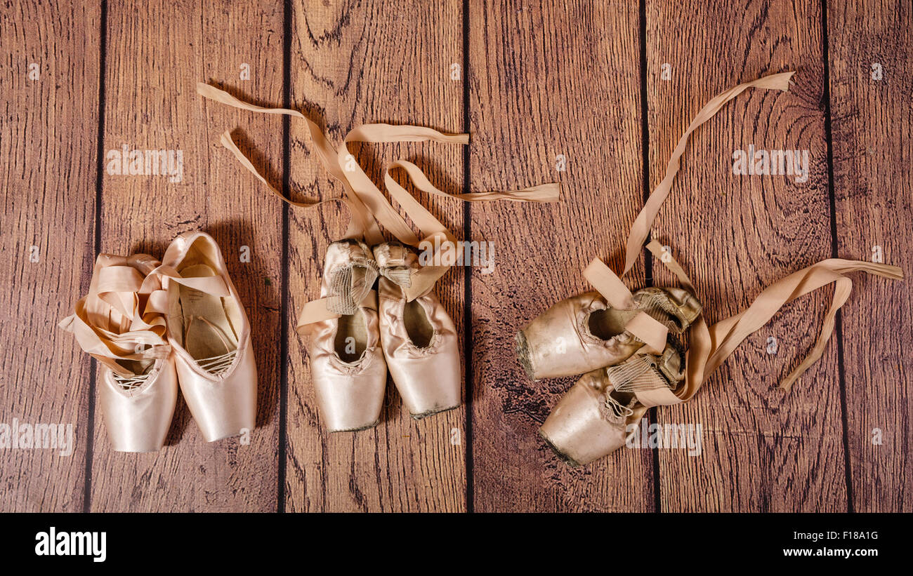 Ballet pointe shoes lie on the wooden floor. Evolution of ballet pointe