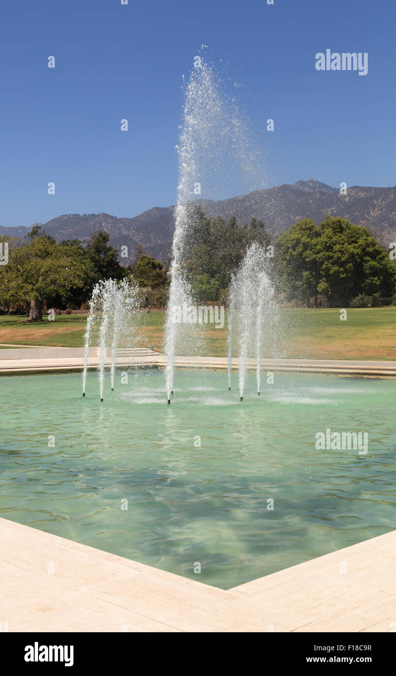 Blue spraying fountain of water with the mountains in the background at Los Angeles Arboretum gardens in California, United Stat Stock Photo