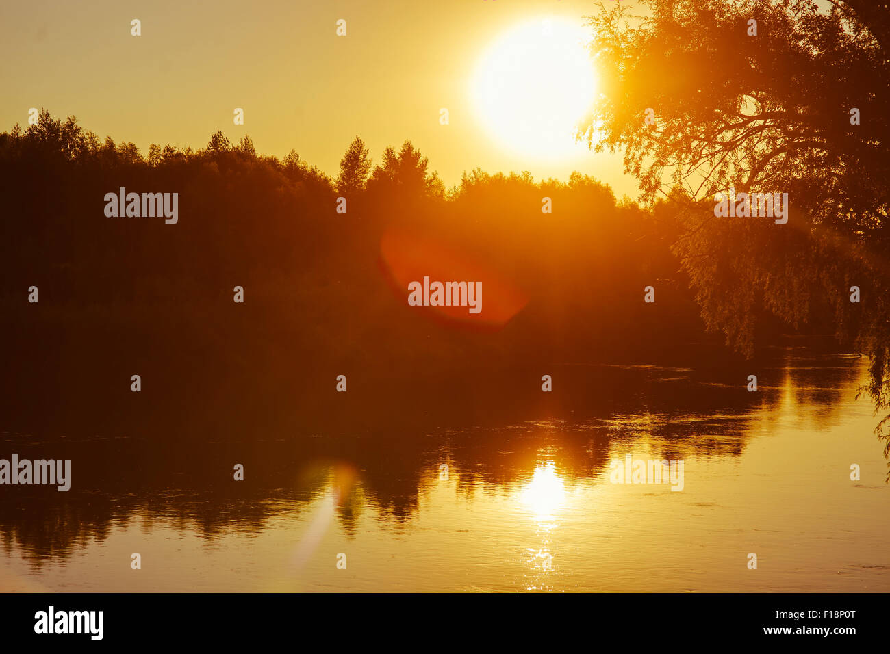 Evening sunset on river sun sets orange light silhouettes the na Stock Photo