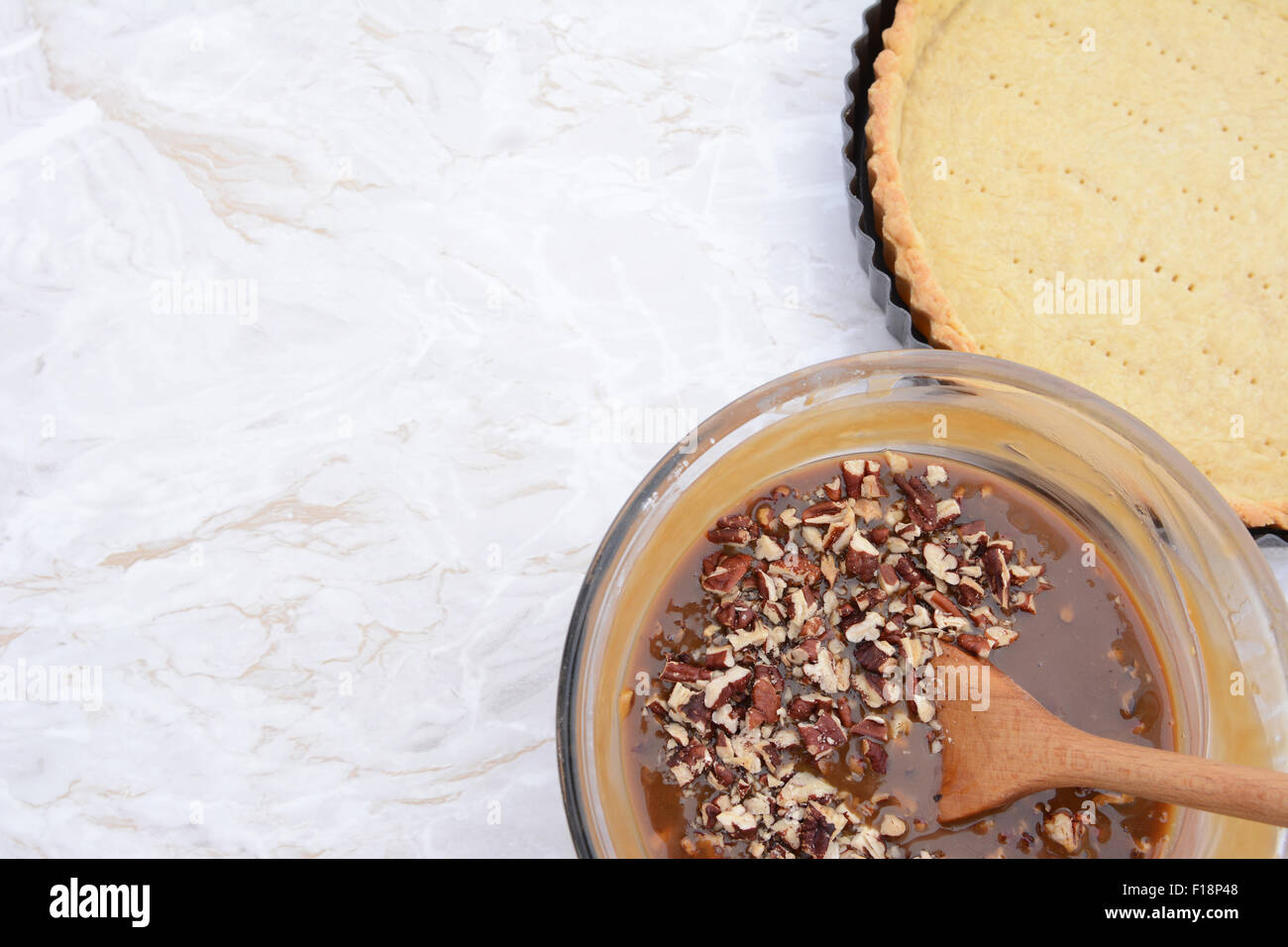 Baking pecan pie - nut-filled pie filling in a bowl next to the prepared pie crust, with copy space on the kitchen worktop Stock Photo